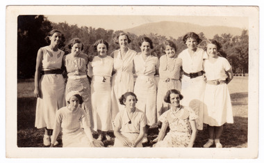 A black and white photograph taken of a ladies cricket team who were staying at Mary-Lyn Guest House in Marysville. Mary-Lyn was part of the Mary Chain of guest houses built by Eric Dowdle in the Depression years. The photograph shows the group of eleven ladies at an unknown location.