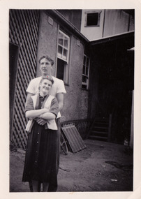 A black and white photograph taken at Mary-Lyn Guest House in Marysville. Mary-Lyn was a part of the Mary Chain of guest houses built by Eric Dowdle in the Depression years. The photograph is of a young man and and lady who worked at Mary-Lyn.