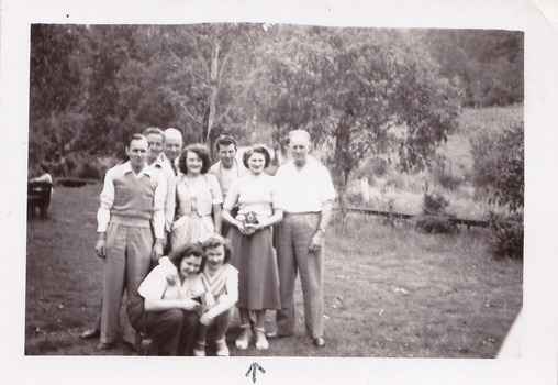 A black and white photograph taken at Mary-Lyn Guest House in Marysville. Mary-Lyn was a part of the Mary Chain of guest houses built by Eric Dowdle in the Depression years. The photograph is of an unknown group of people standing outside in the garden at Mary-Lyn.