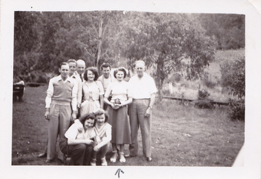 A black and white photograph taken at Mary-Lyn Guest House in Marysville. Mary-Lyn was a part of the Mary Chain of guest houses built by Eric Dowdle in the Depression years. The photograph is of an unknown group of people standing outside in the garden at Mary-Lyn.