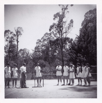 A black and white photograph that was taken at Mary-Lyn Guest House in Marysville. Mary-Lyn was a part of the Mary Chain of guest houses built by Eric Dowdle in the Depression years. The photograph is of an unknown man, possibly Mr. Fred Fiske the proprietor, presenting trophies to a group of people dressed in tennis outfits. The photograph was taken at the tennis court at Mary-Lyn.