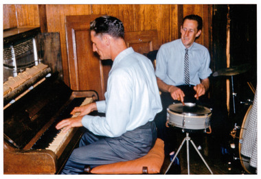 A colour photograph taken at Mary-Lyn Guest House in Marysville. Mary-Lyn was a part of the Mary Chain of guest houses built by Eric Dowdle during the Depression years. The photograph is of Doug Jowett and Sam Ross, musicians, who entertained guests staying at Mary-Lyn. The photograph was taken on 12th January 1961.