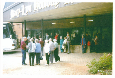 A colour photograph taken at Mary-Lyn Holiday Resort in Marysville. Mary-Lyn was a part of the Mary Chain of guest houses built by Eric Dowdle during the Depression years. The photograph shows several unknown people standing outside the front of the resort.