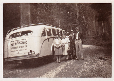 A black and white photograph of a group of passengers alongside a McKenzie's Tourist Services tourist bus. McKenzie's Tourist Services were associated with the growth of Marysville as a tourist destination. The photograph was taken in the 1940s.