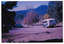 Two colour photographs of a McKenzie's bus travelling along the main street in Marysville. McKenzie's Tourist Services were associated with the growth of Marysville as a tourist destination.
