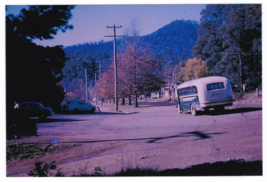 Two colour photographs of a McKenzie's bus travelling along the main street in Marysville. McKenzie's Tourist Services were associated with the growth of Marysville as a tourist destination.