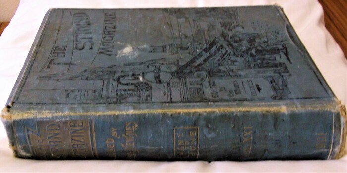 Spine and front cover -  hardcover cloth binding with black and gold lettering and decoration and Strand street scene on front board