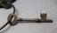 Polished metal watch house key with bow and three prong tip.
