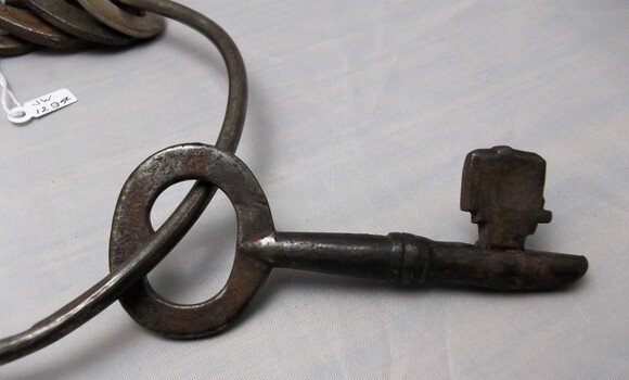 Metal watch house key. Rusty and worn from use. 