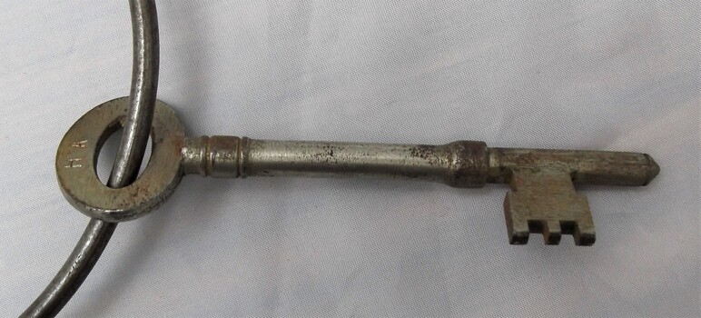 Polished metal key with H A engraved on bow.