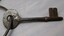 Metal watch house key with bow and two prong tip.