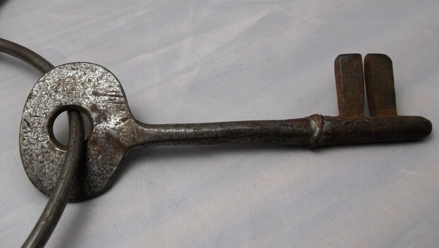 Metal watch house key with bow and two prong tip.