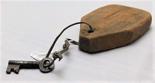 Sideview of key tied to a wooden tag with a leather strap