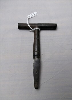 Metal T Bar Key with some wear and tear and A.W engraved on one side