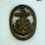 Brass badge with a flower and anchor