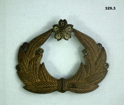 Small gold coloured badge with wreath