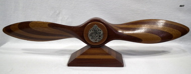 Carved wooden propeller with badge inset
