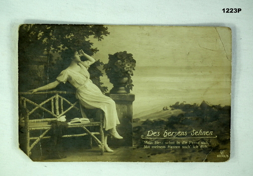 Postcard with a women seated in a garden style surround
