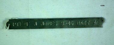 Rectangular pressed name tag with unit details.