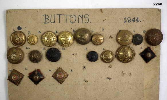 Series of buttons and badges mounted on cardboard.