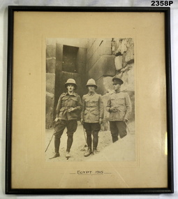 Photo showing three soldiers beside a monument.