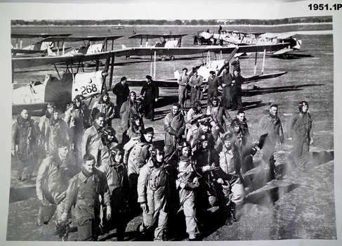 Photo shows a group of airmen with tiger moths in rear.