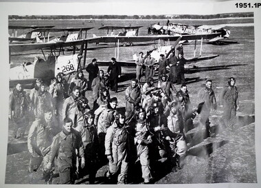 Photo shows a group of airmen with tiger moths in rear.