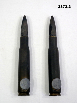Two .50 Cal cartridges with coins attached.