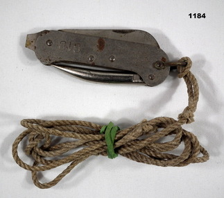 Metal clasp knife with rope cord attached.