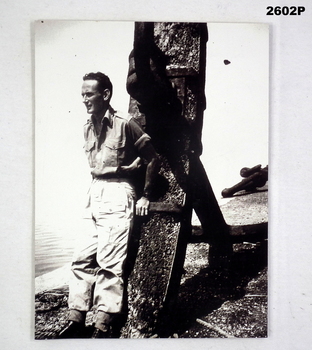 B & W photo of a soldier standing beside an anchor.