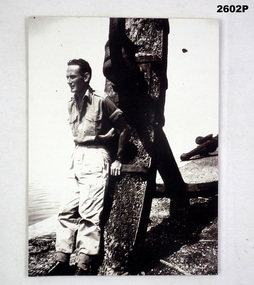 B & W photo of a soldier standing beside an anchor.