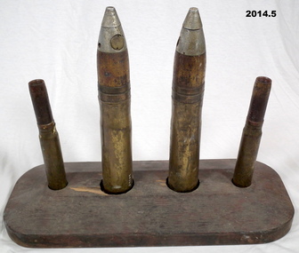 Four ammunition cartridges in a wood stand.