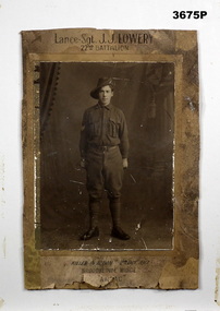 Sepia photo of a soldier in uniform with 3 Sergeant stripes & holding a riding crop