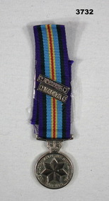 Miniature medal with ribbon and clasp.