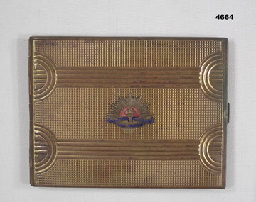 Metal cigarette case with insignia on the front.