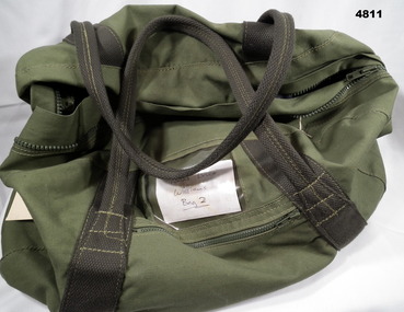 Green army issue kit bag for carrying personal effects.