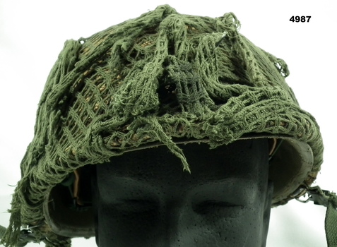 Steel Army helmet with camouflage netting over hessian.