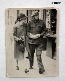 Black & White photograph of lady and soldier walking on street.