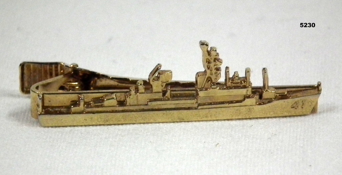 Yellow metal tie clasp in the shape of a ship.