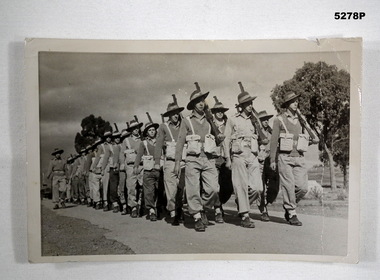 Black & White photo of soldiers marching with Enfield Rifles at the slope.