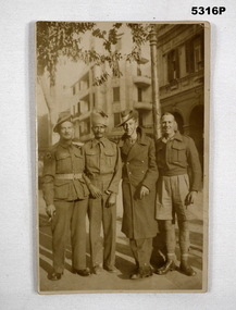 Photograph of four soldiers on a postcard.