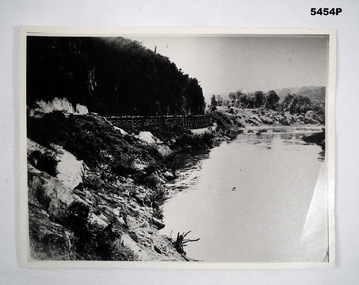 Photograph of a river, hills and rail bridge. Black and white 