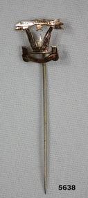 Gold coloured metal badge on a stick pin.