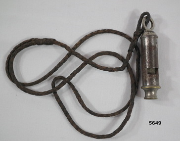Metal whistle with plaited brown lanyard.