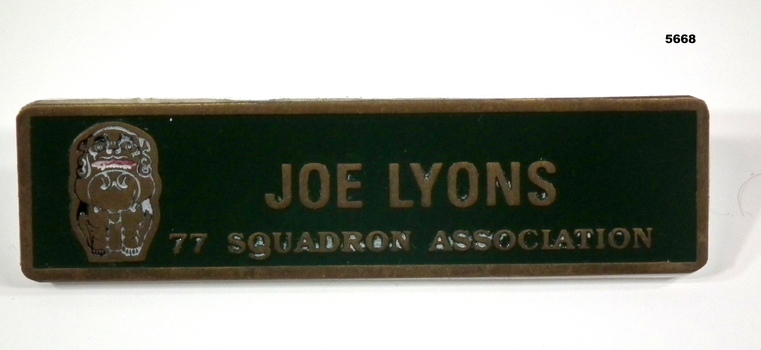 Rectangular name badge with gold coloured lettering.