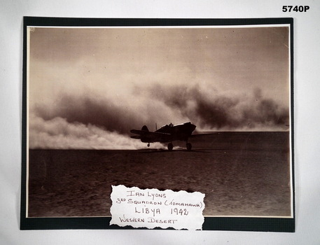 Black and white photograph of a WW2 Tomahawk aircraft on a desert landing strip.