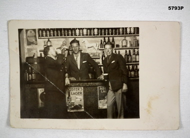 Photograph of three men at a bar having a drink.