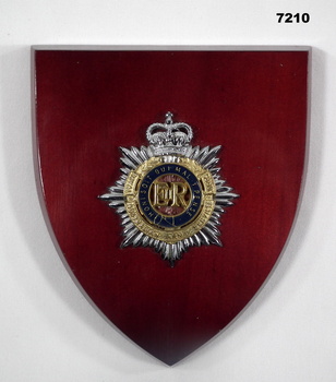 Plaque featuring a RAASC badge on a shield shaped wooden mount.