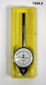 Circular metal instrument with small wheel and dial for measuring distance on a map.
