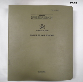 Khaki coloured four ring folder containing a Land Warfare Manual.